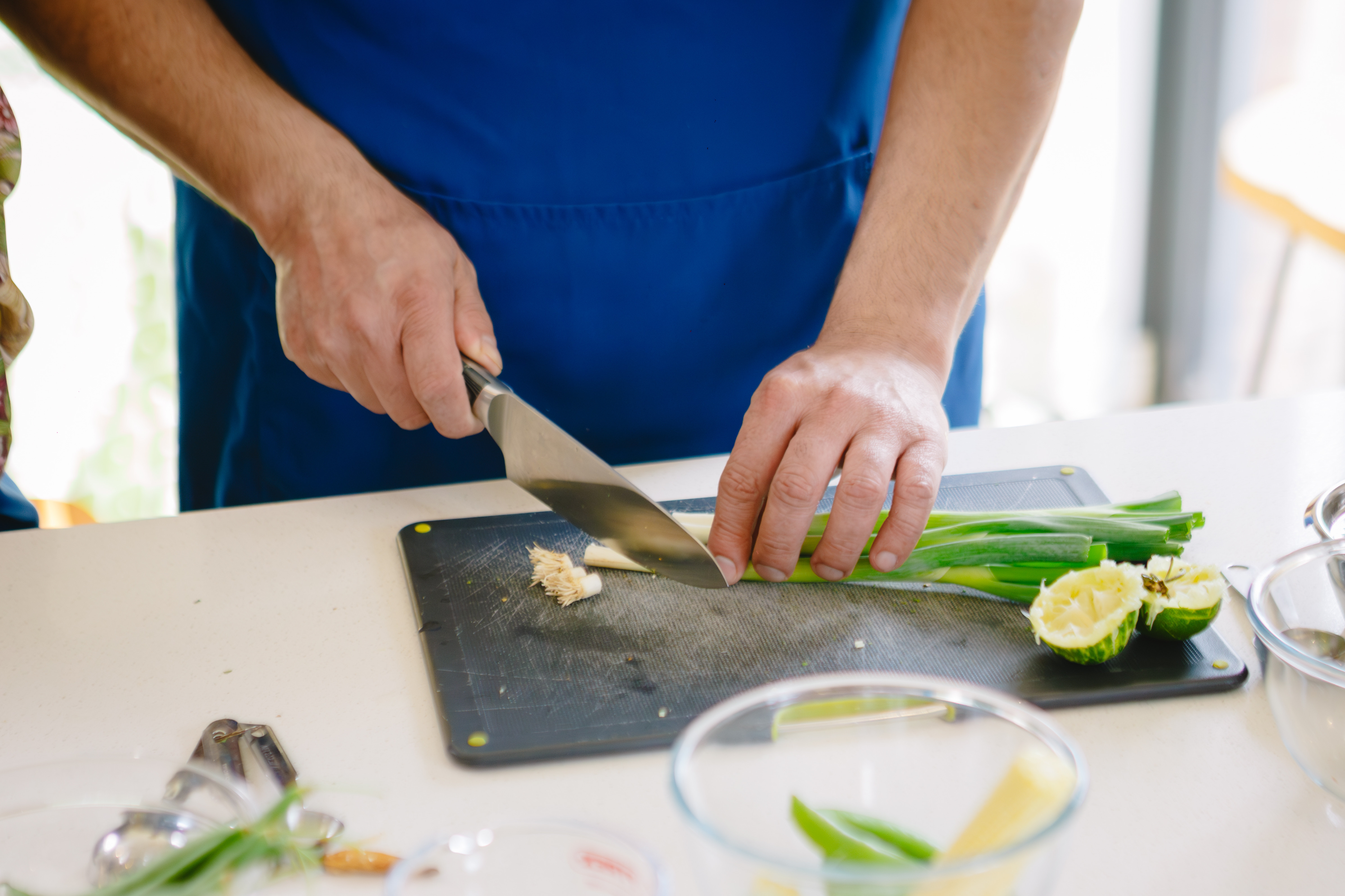 A close up of a person chopping spring onions on a grey chopping board